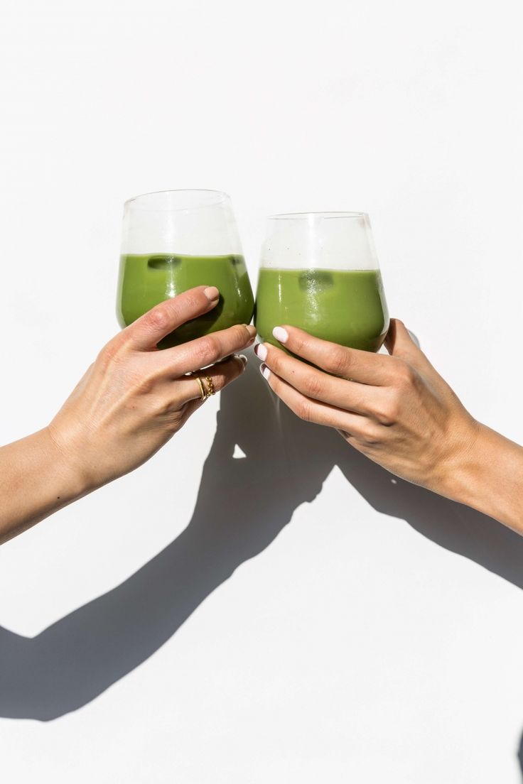 two people with matcha latte in glasses